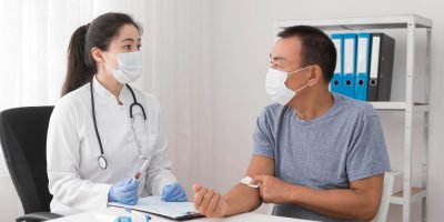 A doctor checking a patient. Both are in surgical mask.