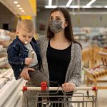A young woman with her baby Infront of super shop Gondola Racks.