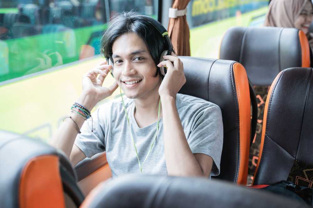 A young man in Bus, listening to music with headphones.